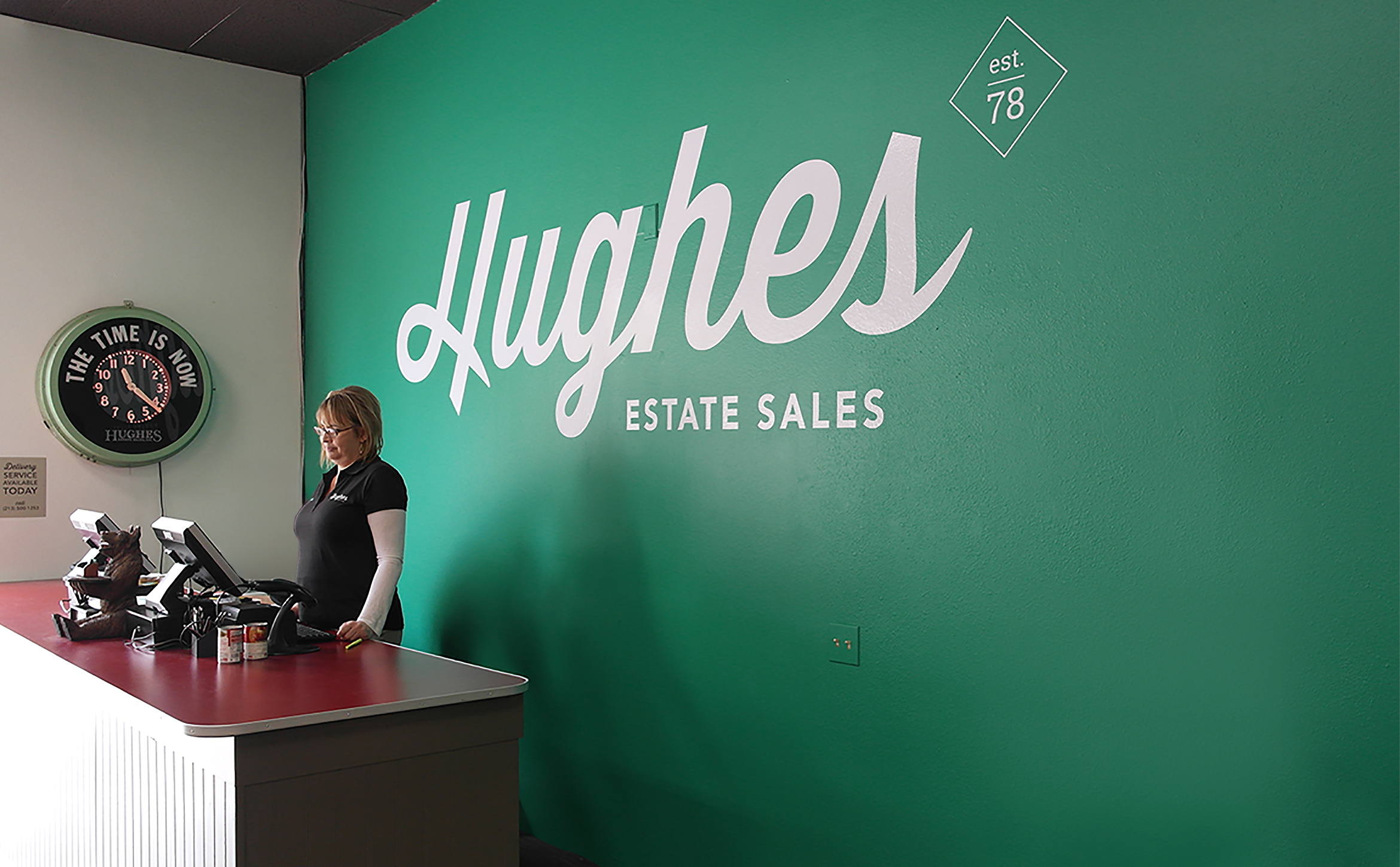 hughes estate sales logo white on green wall inside the showroom