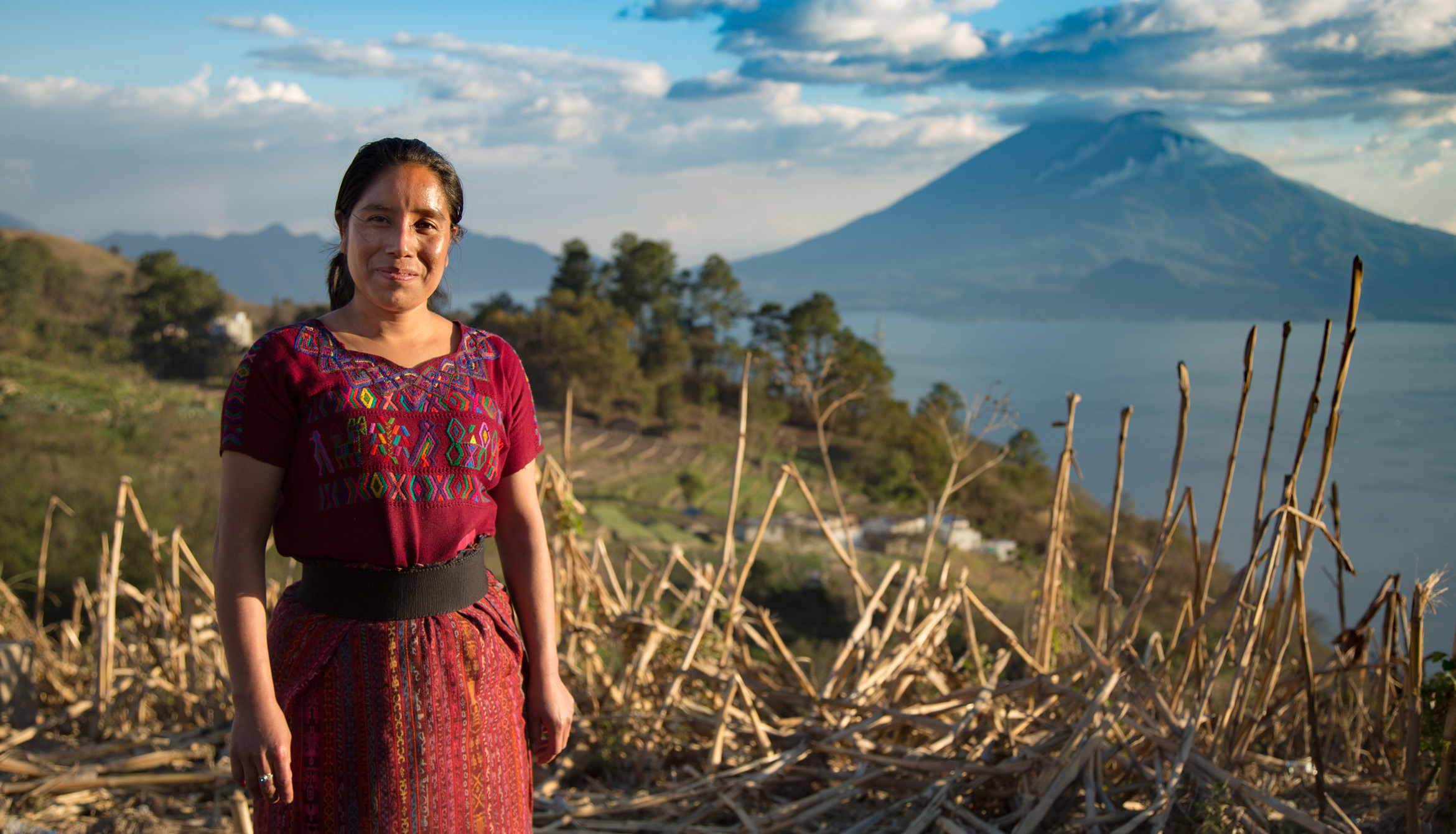 honduran woman doctor standing outside by lake with mountain in red dress