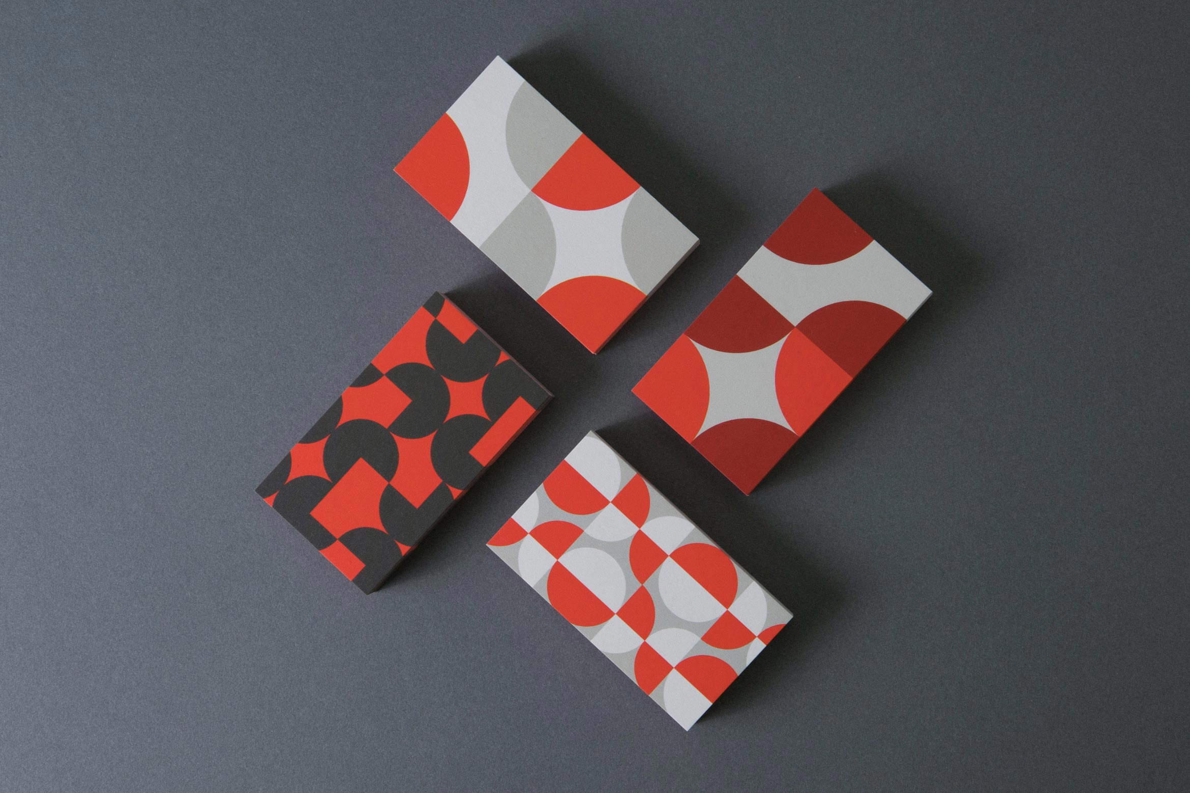 overhead shot of 4 business card designs using quarter and half circles on gray
