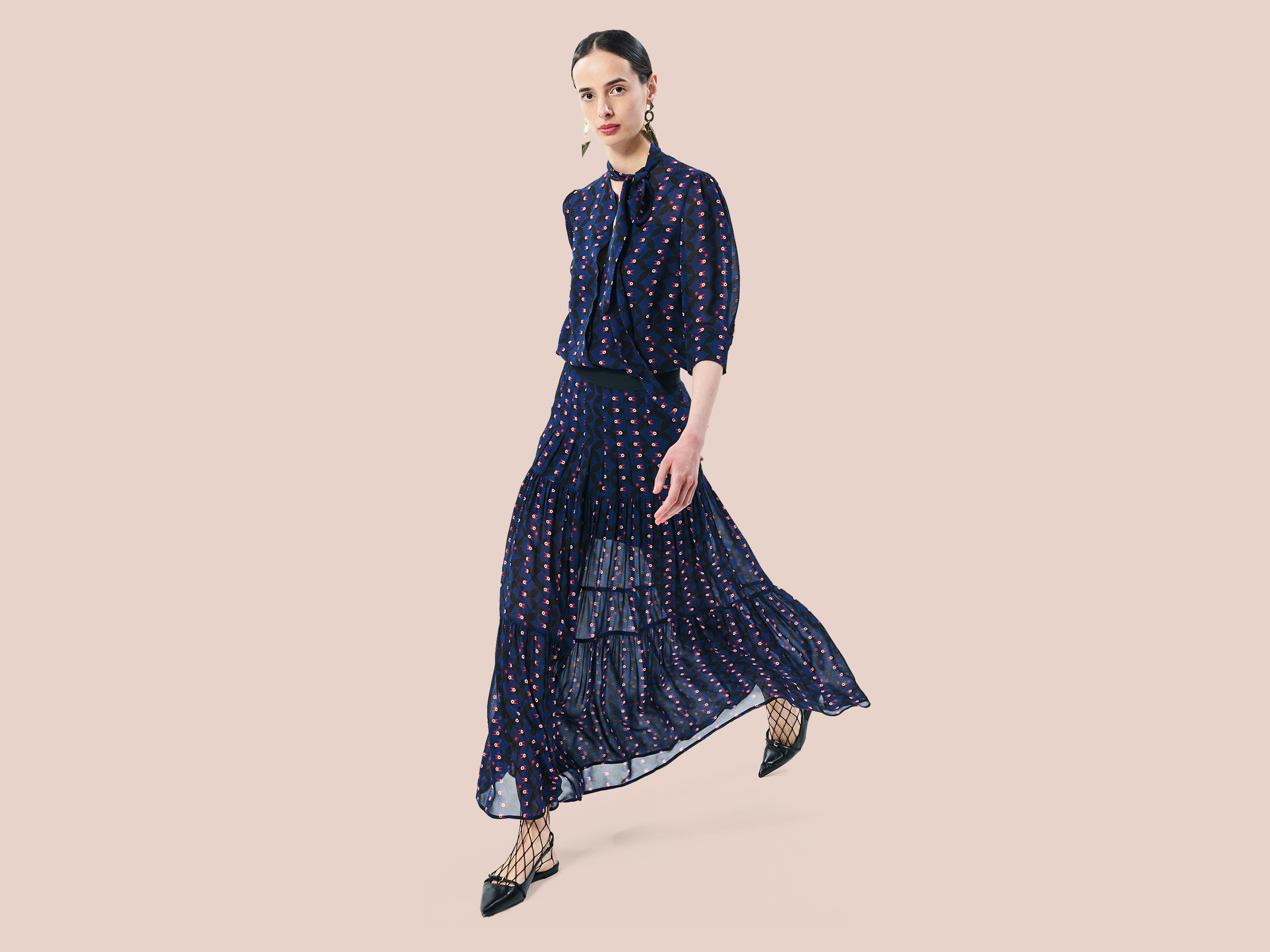 brunette woman full body wearing a pussy bow blouse and skirt in navy blue with crows pattern in black, white