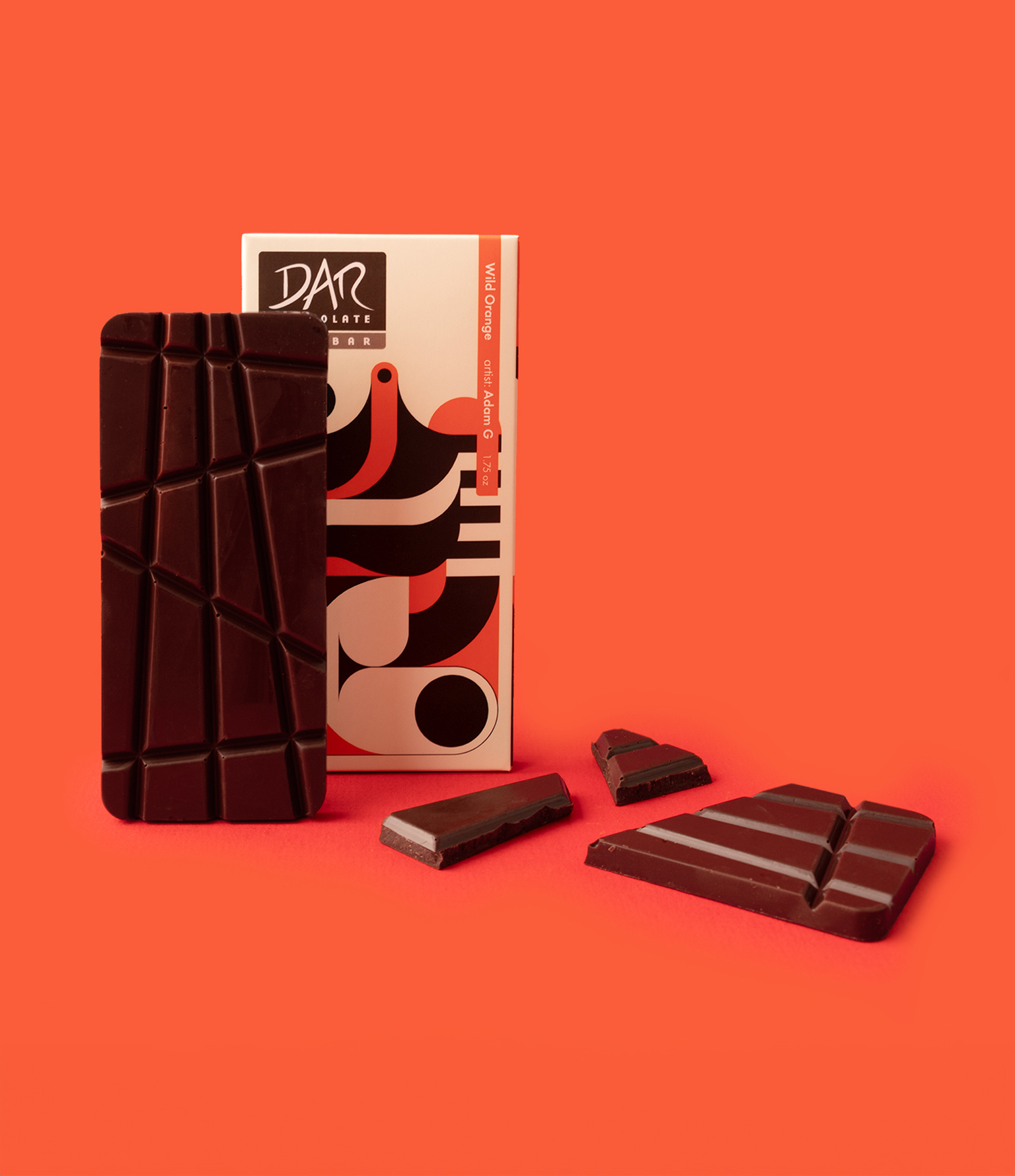 DAR chocolate bar in front of its packaging with 23 design and pieces of chocolate on orange baccground
